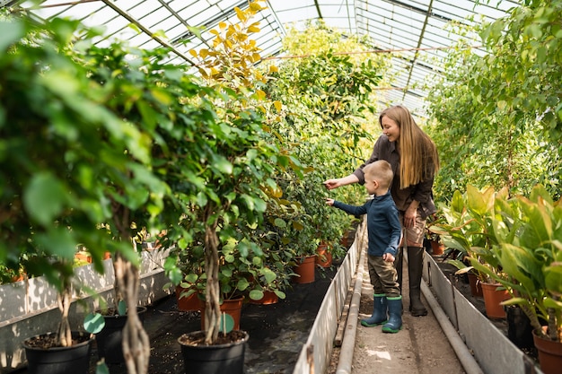 Mamma e figlio camminano in una serra di fiori