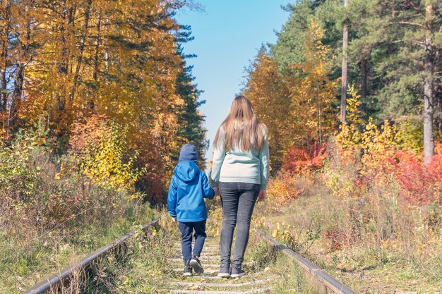 Mamma e figlio che fanno un'escursione sulla ferrovia abbandonata al giorno di autunno soleggiato