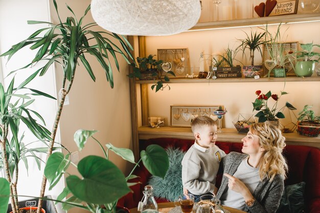 Mamma e figlio con fiori in caffe. Il figlio dà i fiori alla madre. famiglia carina. Giornata internazionale della donna, 8 marzo celebrativa