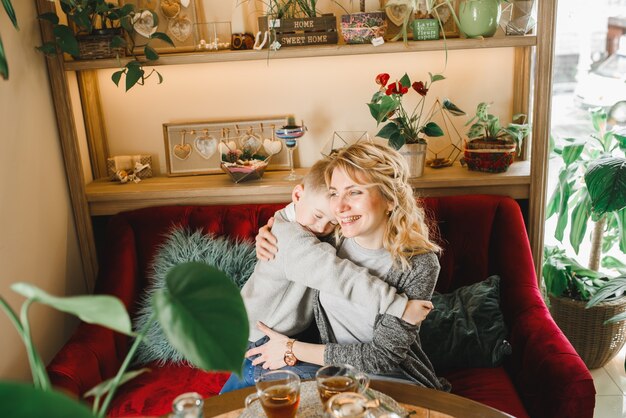 Mamma e figlio con fiori in caffe. Il figlio dà i fiori alla madre. famiglia carina. Giornata internazionale della donna, 8 marzo celebrativa