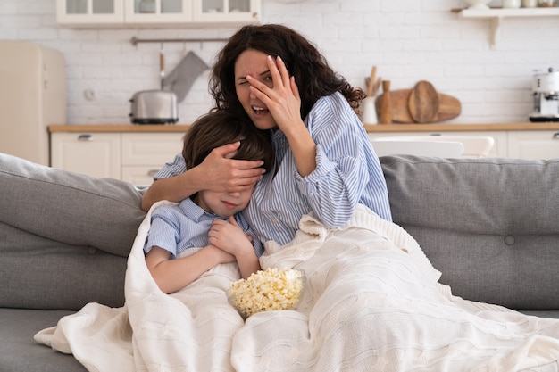 Mamma e figlio con una ciotola di popcorn guardando film spaventoso