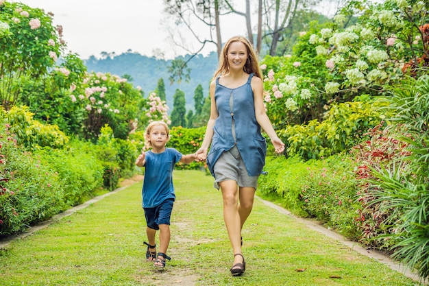 Mamma e figlio corrono nel giardino fiorito felice concetto di stile di vita familiare