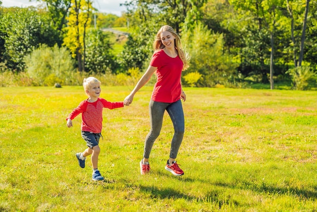 Mamma e figlio corrono sull'erba verde Famiglia felice nel parco