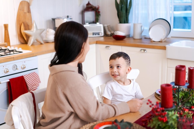 Mamma e figlio divertiti a giocare in cucina felici a passare il tempo la vigilia di Natale e la vigilia di Capodanno