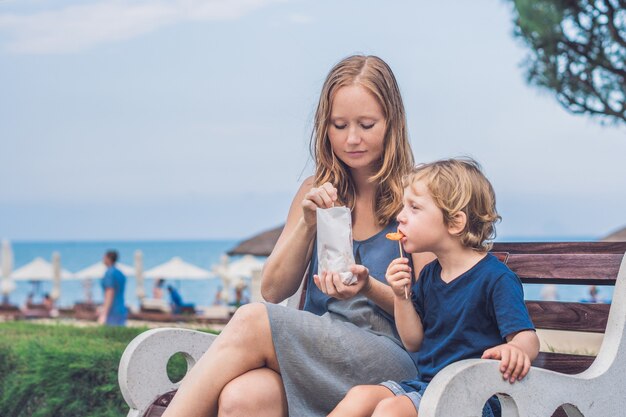 Mamma e figlio mangiano patate dolci fritte nel parco. Concetto di cibo spazzatura.