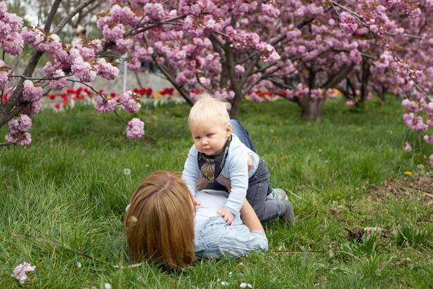 Mamma e figlio piccolo nella natura che giocano al parco primaverile Il bambino e la madre si divertono durante le attività del fine settimana nei giardini fioriti di Sakura