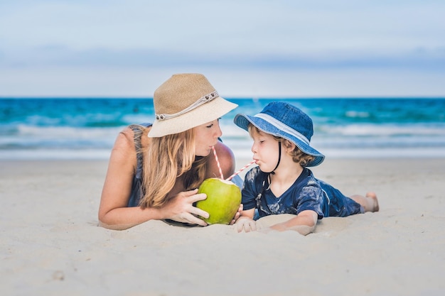 Mamma e figlio si godono la spiaggia e bevono cocco