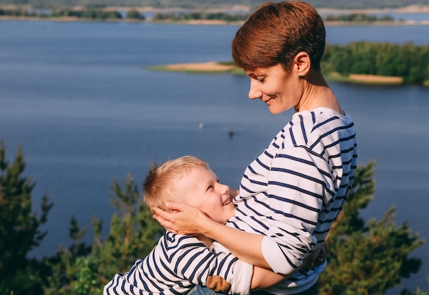 Mamma e figlio stanno abbracciando sfondo di un grande fiume