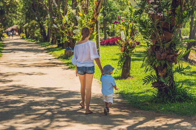 Mamma e figlio stanno camminando nel parco tropicale.