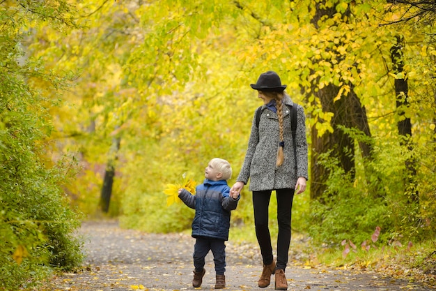 Mamma e figlio stanno camminando nella foresta autunnale.