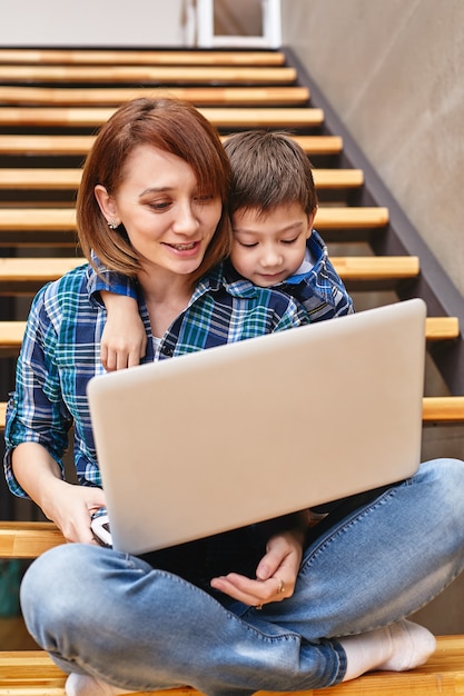 Mamma e figlio stanno facendo i compiti al computer. Concetto mamma e bambini, tecnologia moderna e Internet.