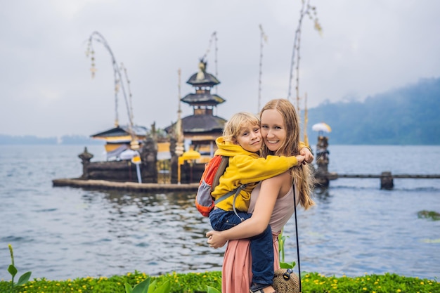 Mamma e figlio sullo sfondo del tempio indù di pura ulun danu bratan bali circondato da fiori