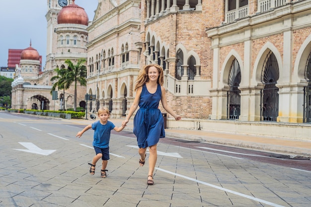 Mamma e figlio sullo sfondo dell'edificio del sultano Abdul Samad a Kuala Lumpur, in Malesia. Viaggiare con il concetto di bambini