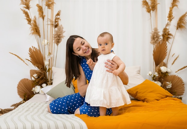 Mamma felice che gioca con la piccola figlia sul letto in camera da letto