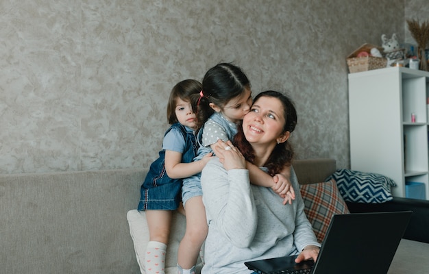 Mamma felice che lavora a casa sul computer circondato da bambini piccoli