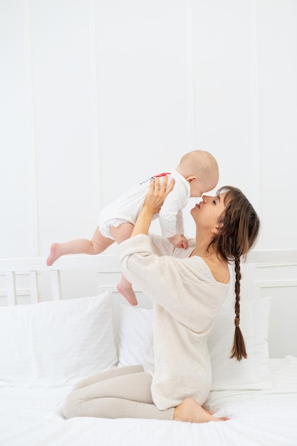 Mamma felice con una bambina a casa sul letto abbraccia e bacia felice giovane madre e maternità