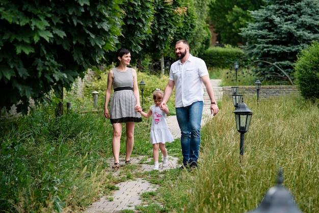 Mamma incinta, figlia e papà stanno camminando nel parco.