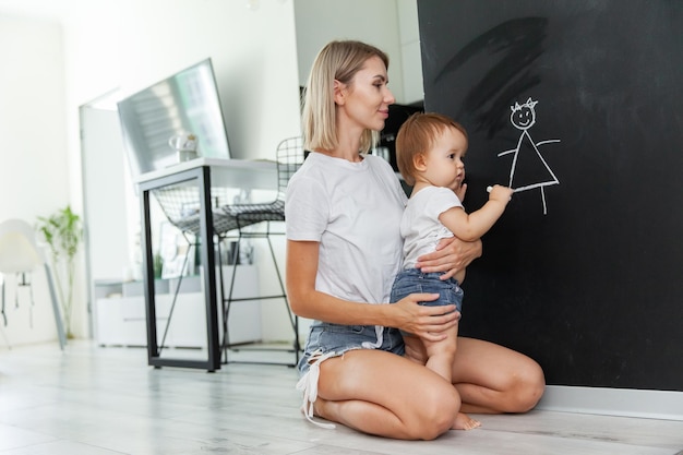 Mamma insegna a sua figlia a disegnare su una tavola di resina a casa