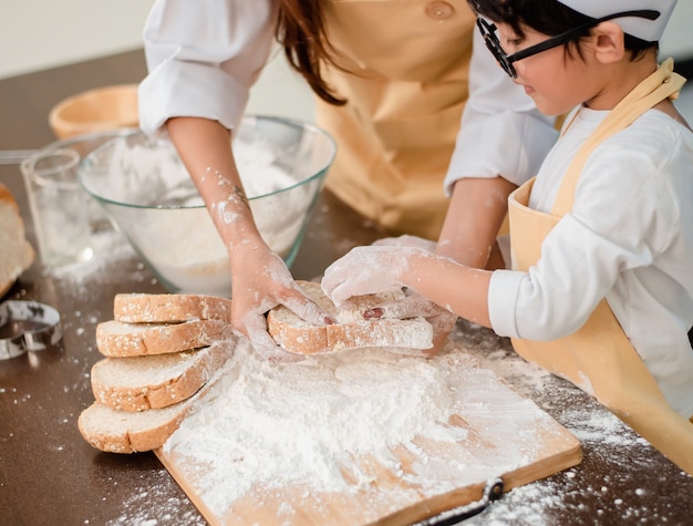 Mamma insegna al figlio a cucinare il cibo. Madre e figlio stile di vita quotidiano a casa. Famiglia asiatica insieme in cucina.