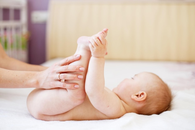 Mamma Mamma fa ginnastica per un bambino Madre che massaggia il bambino in un letto a casa