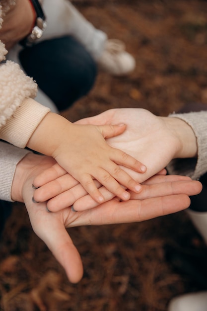 Mamma, papà e bambino si tengono per mano durante una passeggiata in autunno Mani di famiglia e supporto degli adulti Una famiglia felice