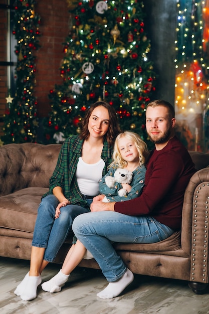 Mamma, papà e figlia di famiglia svegli pongono all'albero di Natale