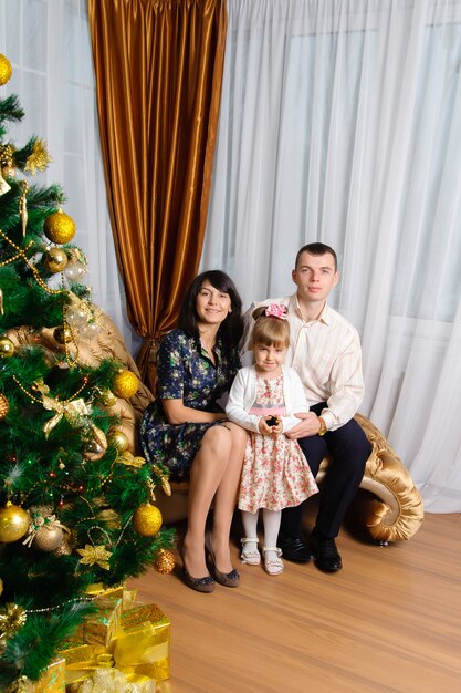 Mamma, papà e figlia in posa con l'albero di Natale