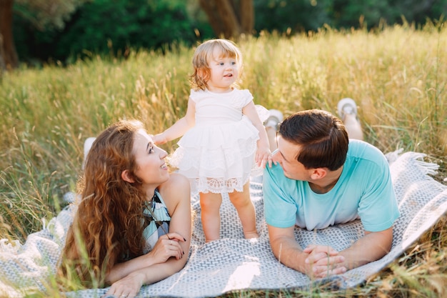 Mamma, papà e figlia insieme su una stuoia all'aperto.