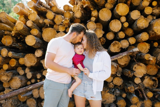 Mamma papà e il loro figlioletto si stanno baciando in un mucchio di tronchi d'albero