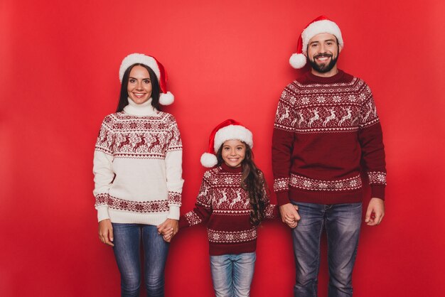 Mamma papà piccola donna con capelli castani ricci in costumi tradizionali lavorati a maglia Natale