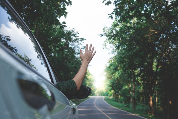 Man driver sentire il vento attraverso le mani mentre si guida in campagna.