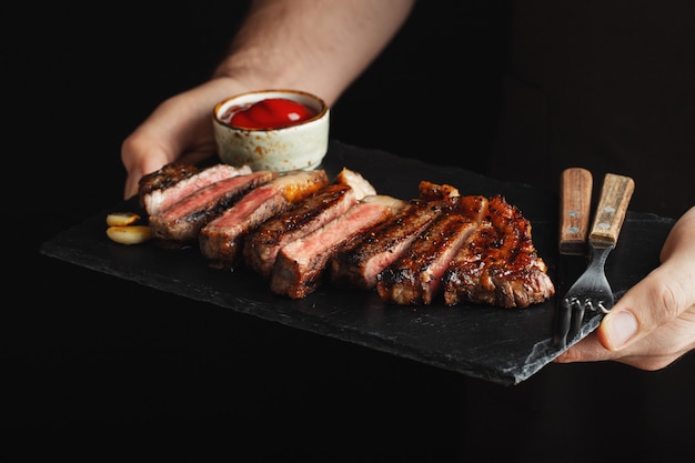 Man holding bistecca di manzo alla griglia succosa.