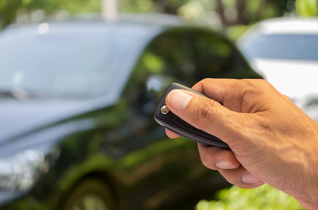 Man mano che tiene la chiave dell'auto pronta per avviare una nuova auto con sfondo sfocato dell'auto