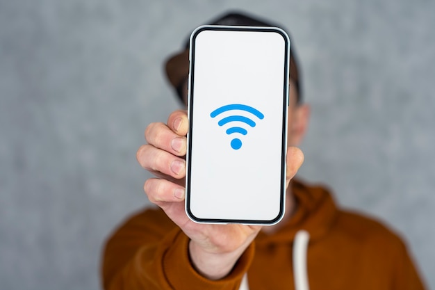 Man mano che tiene smartphone argento isolato su sfondo chiaro. Modello di telefono con schermo bianco e icona Wi-Fi.