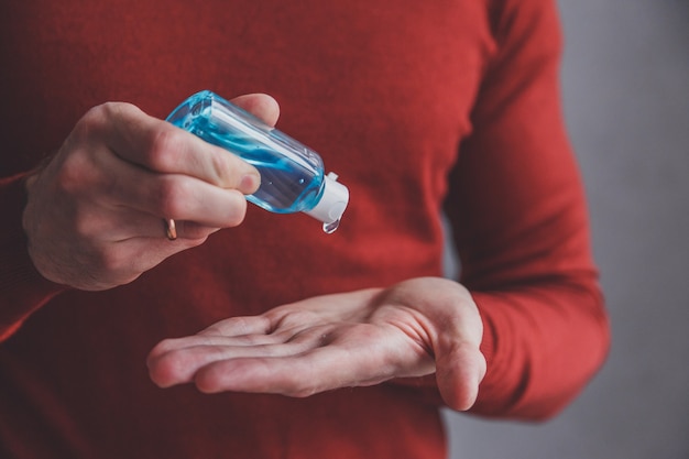 Man mano che utilizza il dispenser di gel disinfettante per le mani, coronavirus Covid-19 in luoghi pubblici