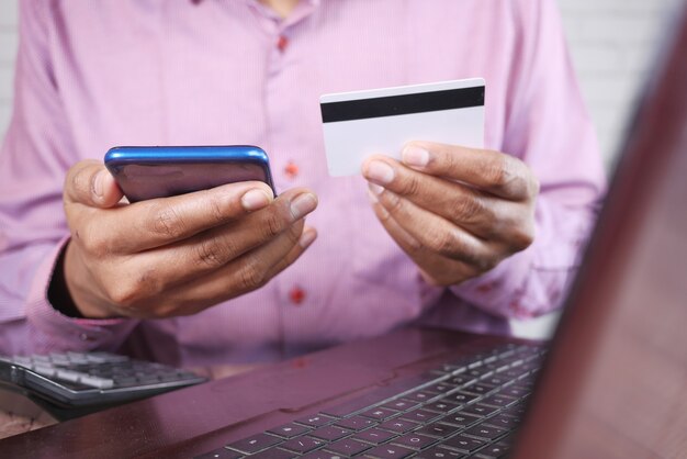 Man mano con carta di credito e utilizzando smart phone acquisti online