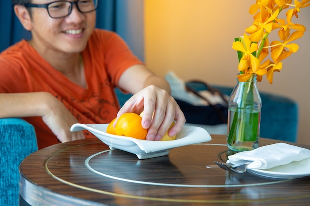 Man pick orange dal piatto, concetto di frutta sana