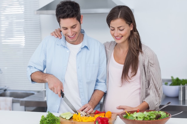 Man tagliare le verdure accanto al suo partner pregano