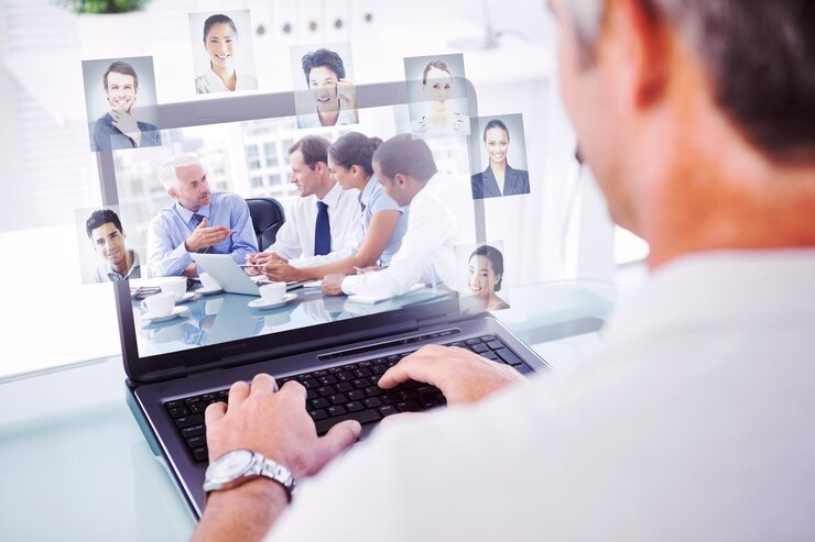 Photo man with grey hair typing on laptop against group of business people brainstorming together