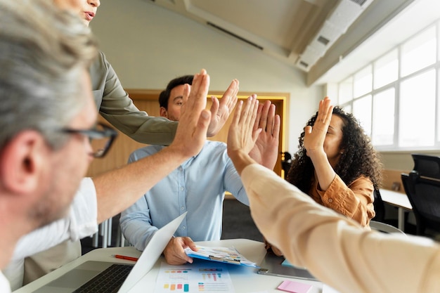 manager attraenti uomini d'affari che danno il cinque seduti sul posto di lavoro in un ufficio moderno