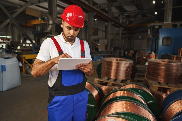 Manager maschio afroamericano nel magazzino di cavi elettrici con tablet digitale