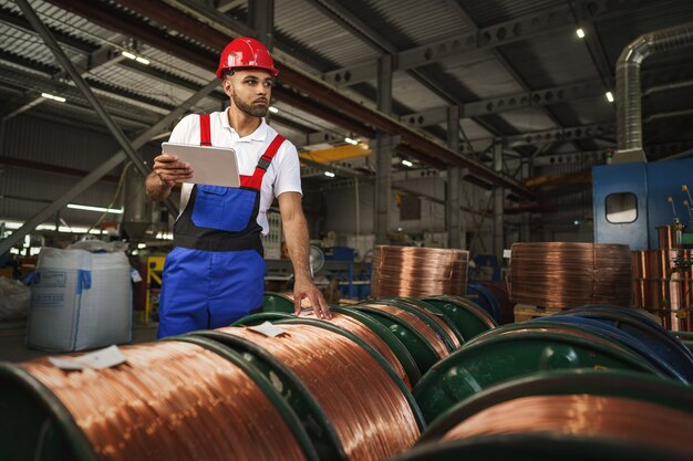 Manager maschio afroamericano nel magazzino di cavi elettrici con tablet digitale