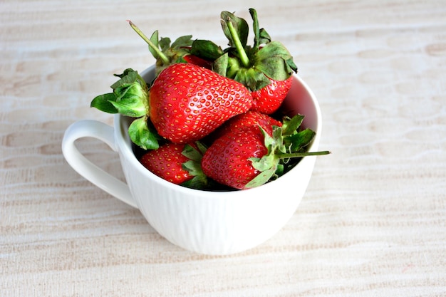 manciata di fragole da giardino in tazza bianca isolata, primo piano