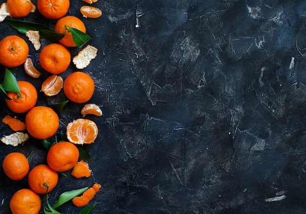 Mandarini con foglie su fondo scuro