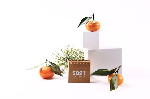 Mandarini e un ramo di abete, un calendario 2021 e una lettera su sfondo bianco. Concerto di Natale minimalista scandinavo creativo