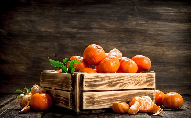 Mandarini maturi in una vecchia scatola su uno sfondo di legno
