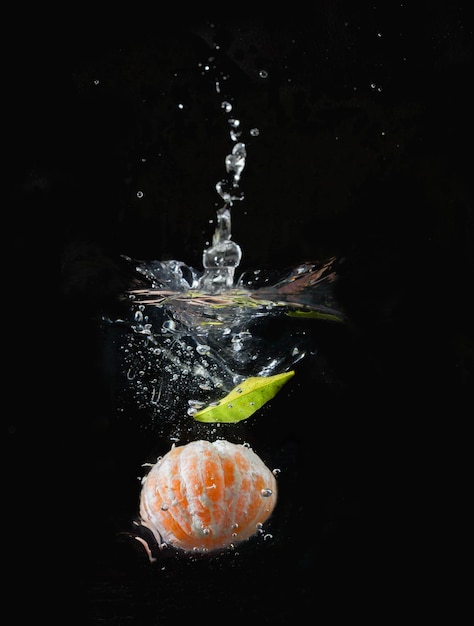 Mandarino con bollicine immerso in acqua con fondo nero Vitamina c