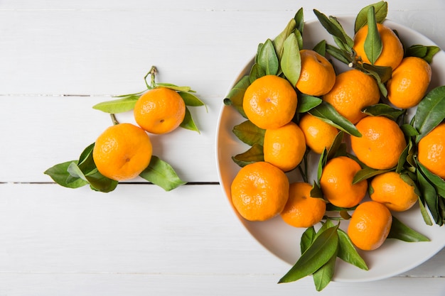 Mandarino mandarini con foglie in un piatto bianco. Vista dall'alto,