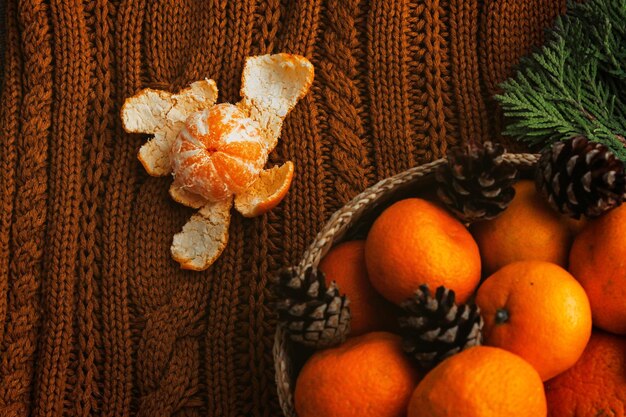 Mandarino sbucciato su cesto di superficie di lana con mandarini accanto