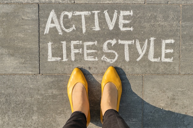 Mandi un sms allo stile di vita attivo scritto su pavimentazione grigia con le gambe della donna, vista da sopra